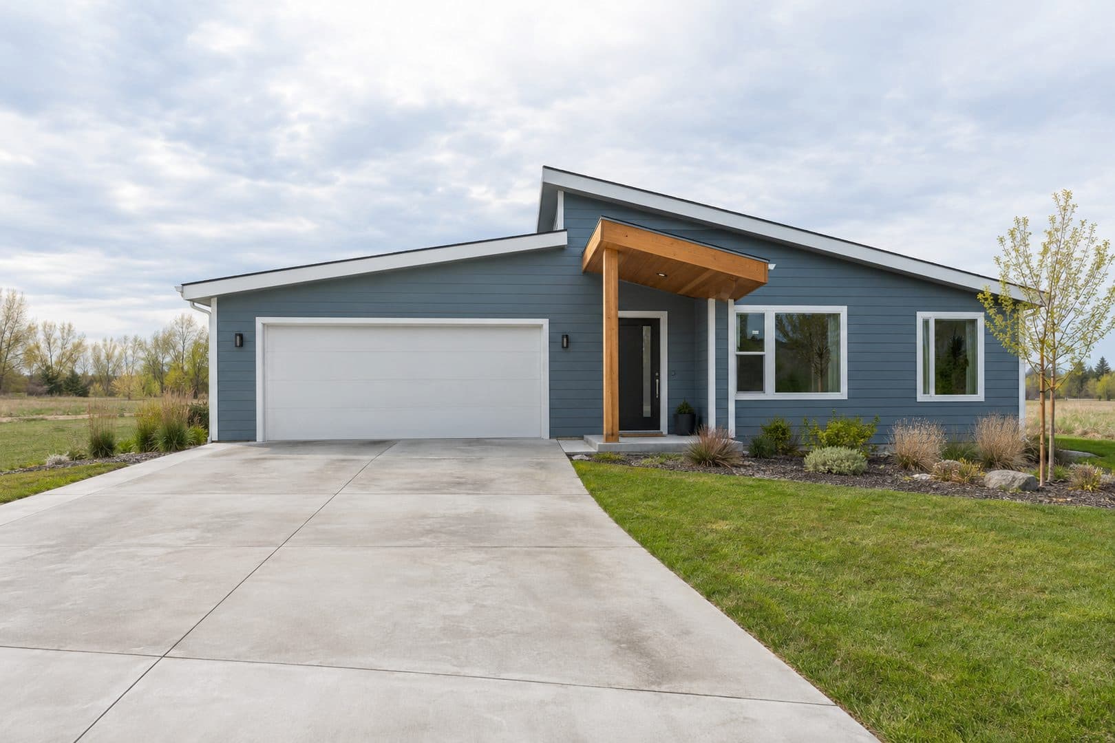 Blue single-story home with an asymmetrical roof, wooden entry canopy and attached garage