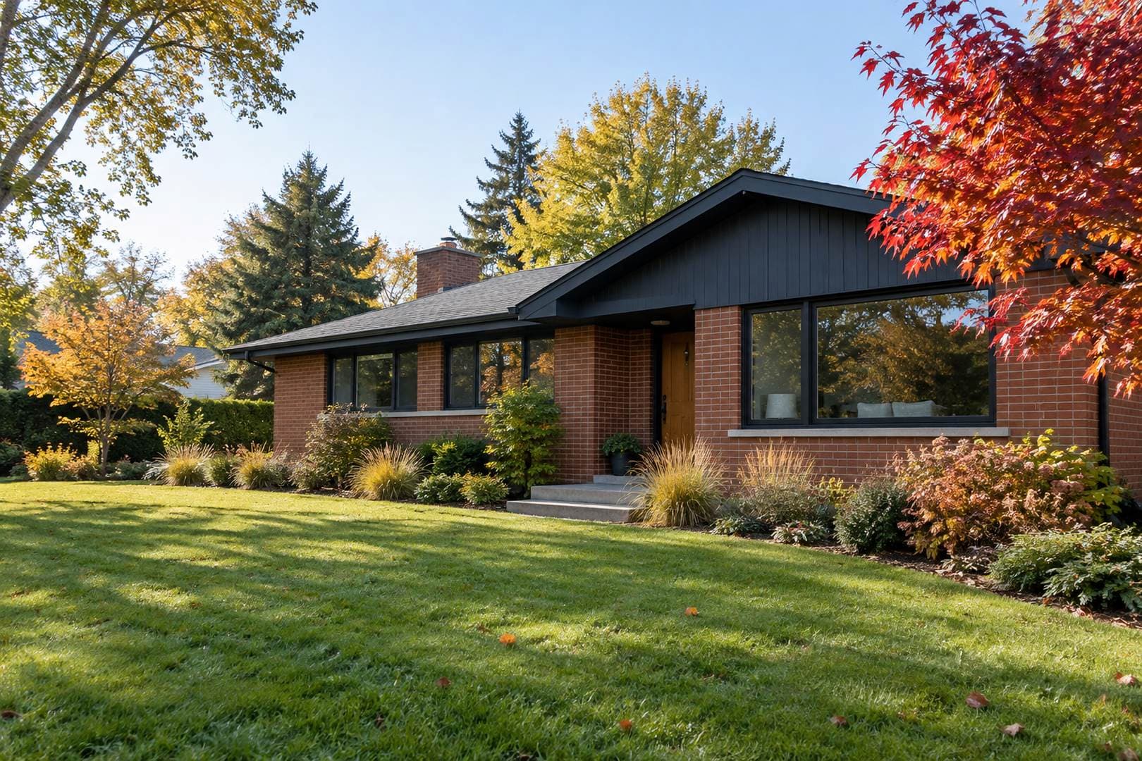 Single-story brick house with dark window trim, a landscaped front garden and autumn trees